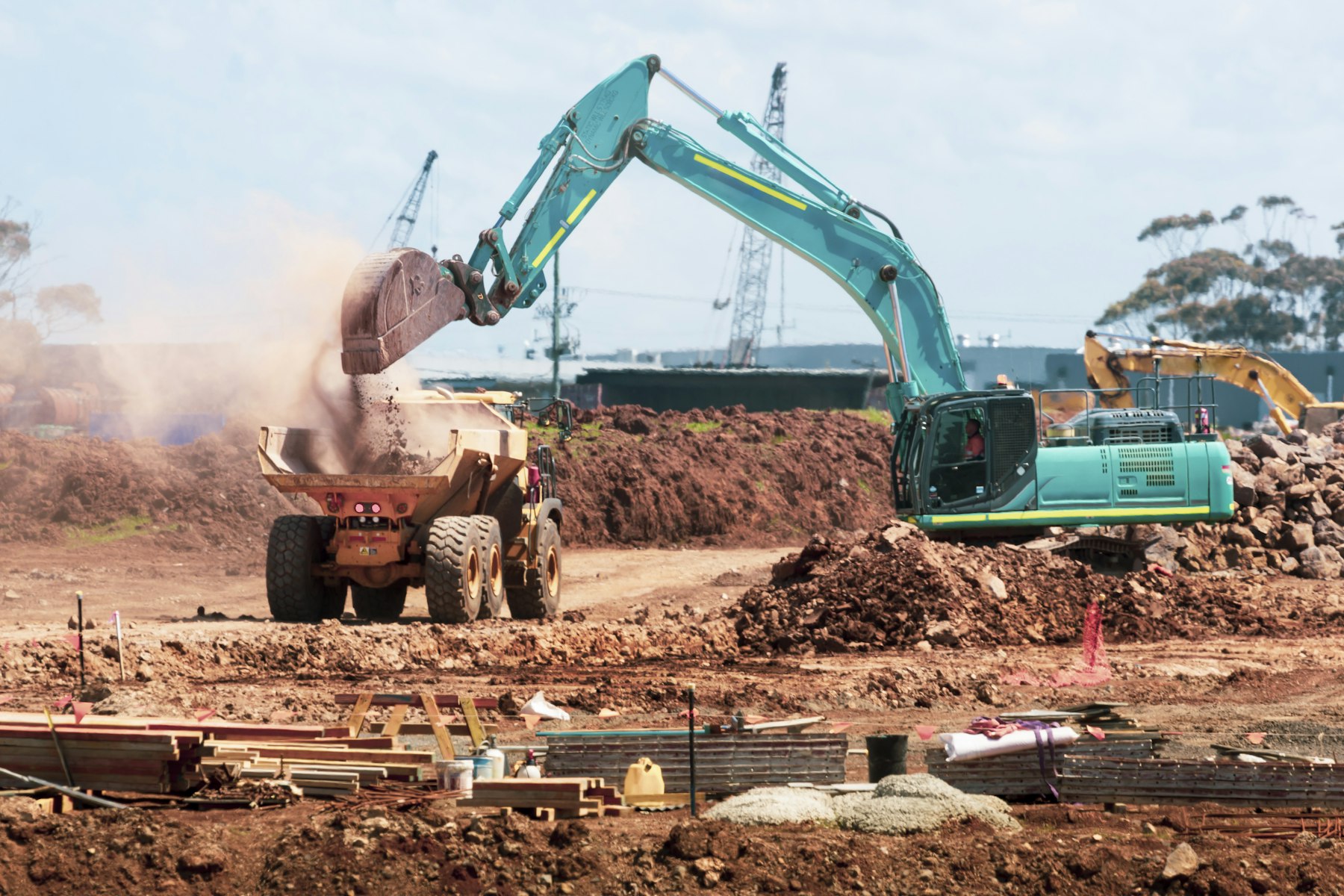 An excavator dumping soil into a truck on a construction site