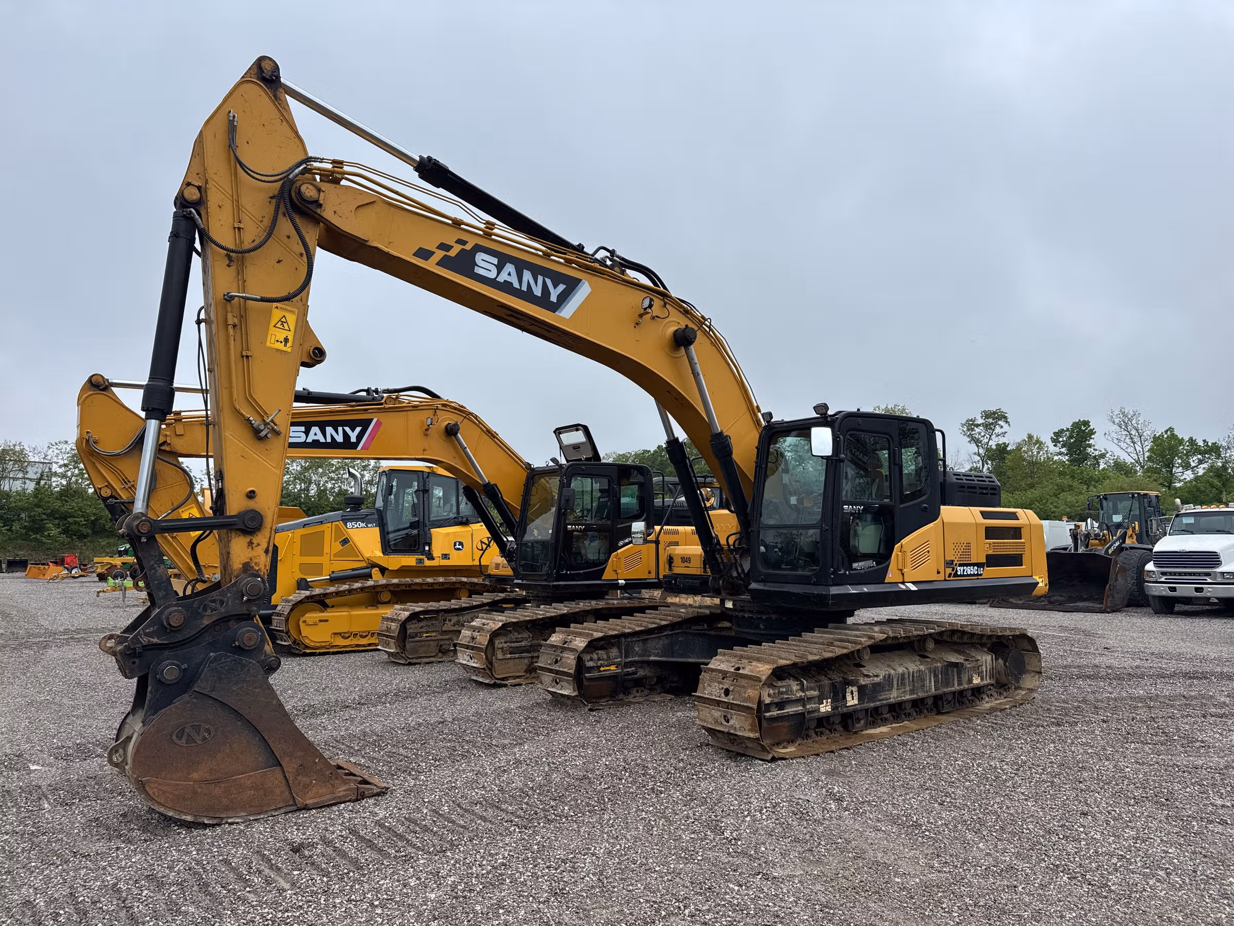 A row of yellow and blue construction machines parked in a yard
